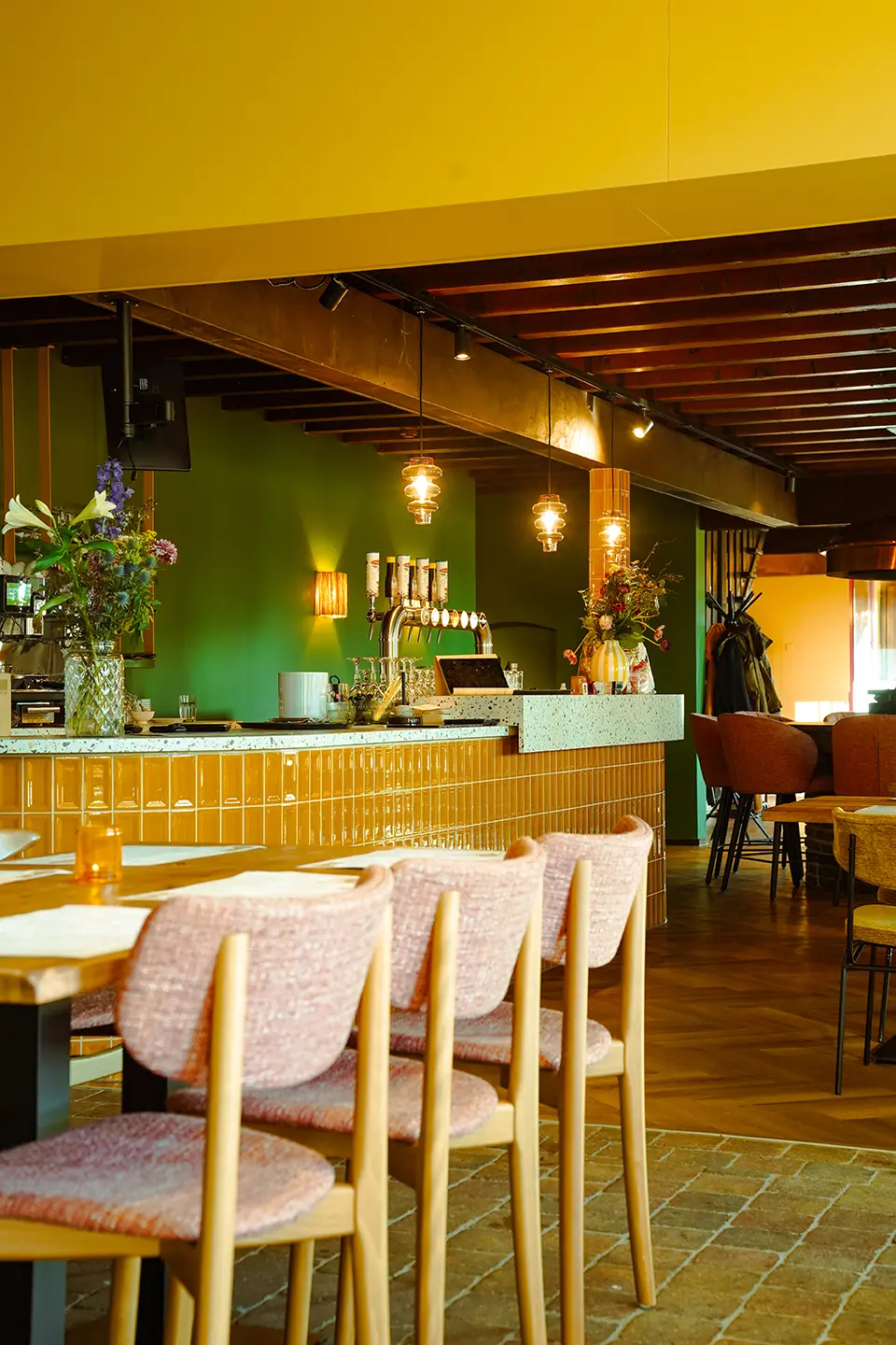 De bar met tapkranen, hanglampen en een bos bloemen