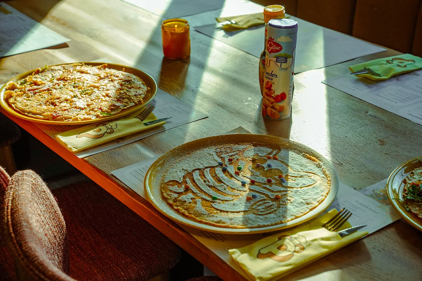 Twee pannenkoeken op tafel in het middagzonlicht, met een flesje limonade
