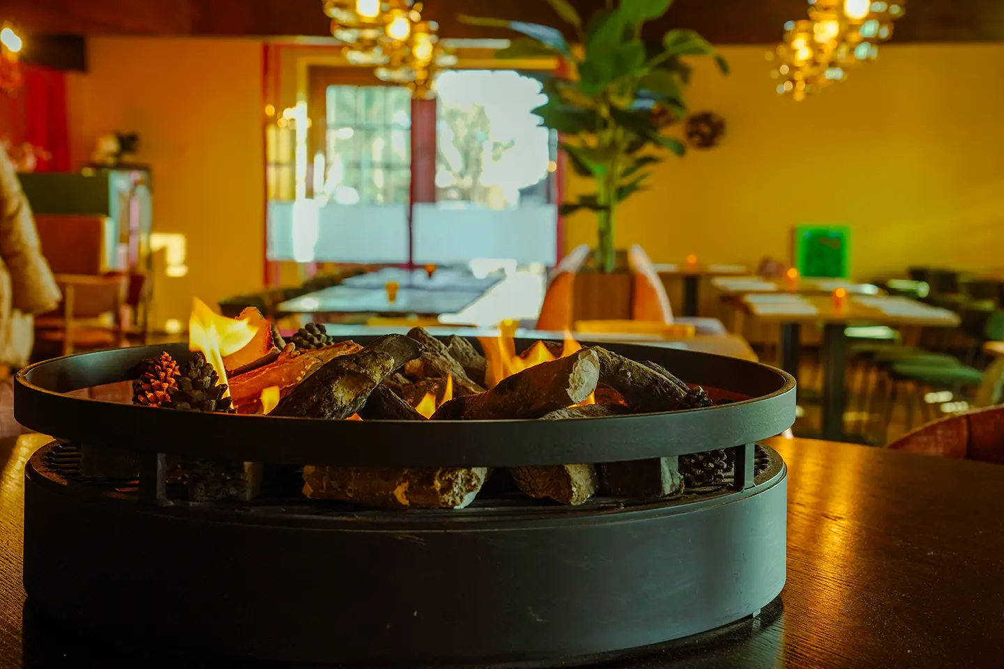 Vuurschaal met vlammen op tafel, met het restaurant op de achtergrond