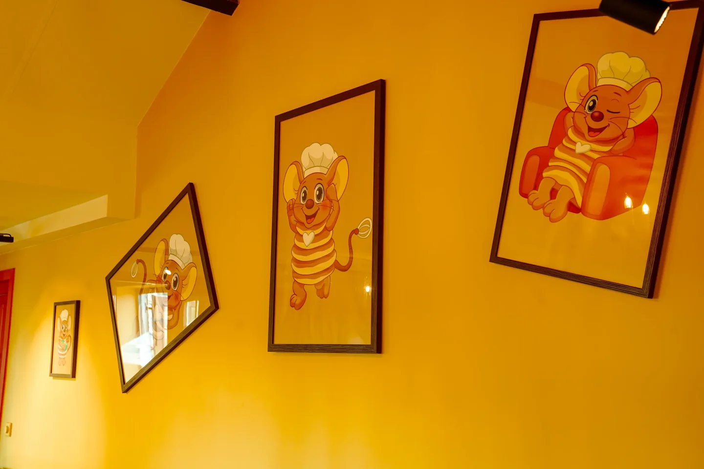 Ingelijste tekeningen van Pluis de pannenkoekenmuis aan een gele muur