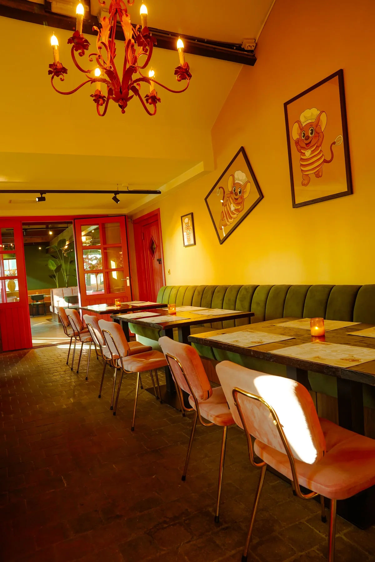 Warm verlichte zaal met een rode kroonluchter en een groene bank langs de muur