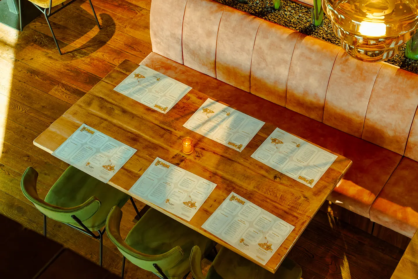 Gedekte tafel met placemats en kaarten langs een roze bank