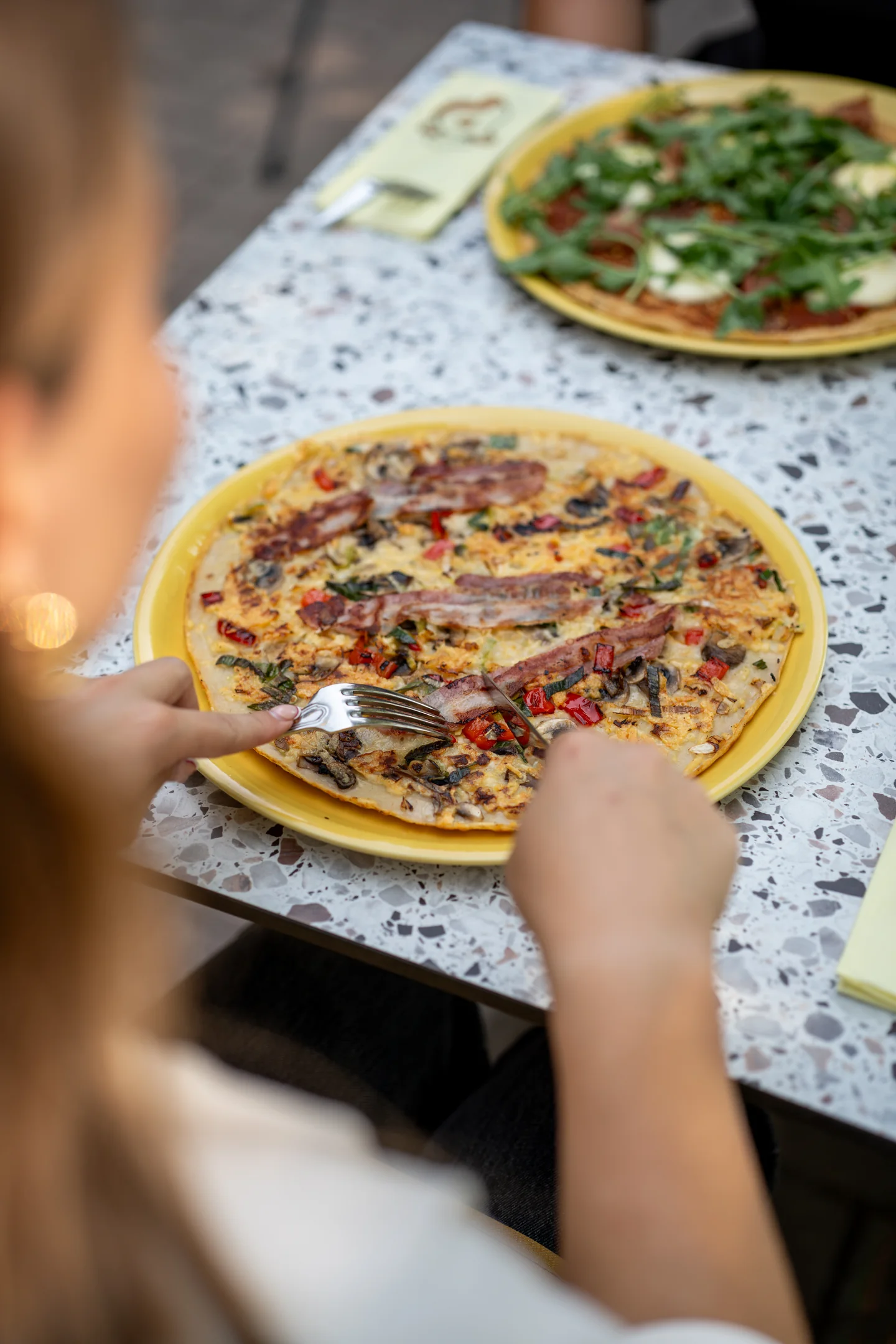 Hartige pannenkoek met spek en groenten op geel bord op het terras van Pluis