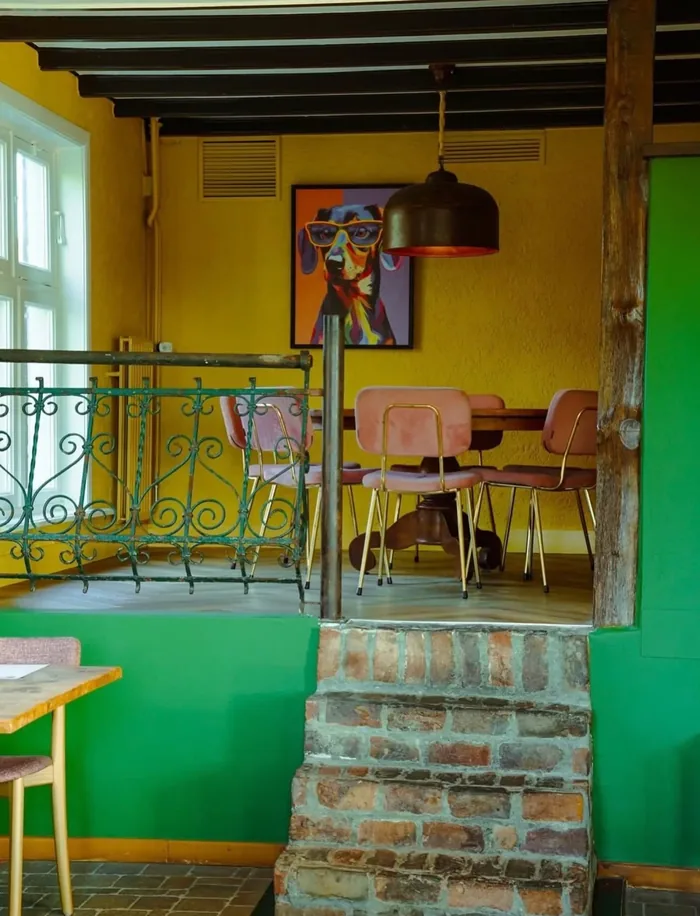 Hoekje met een groene muur, een bakstenen trapje en een kleurrijk schilderij