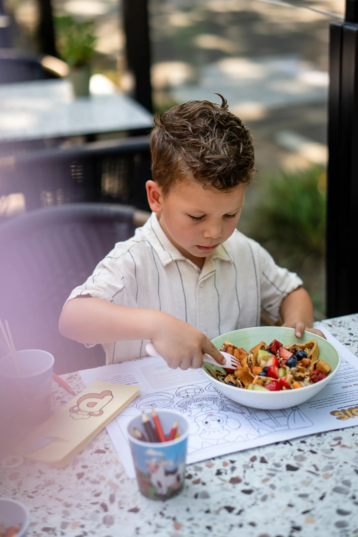 Kind eet fruit en wafel op het terras van Familierestaurant Pluis