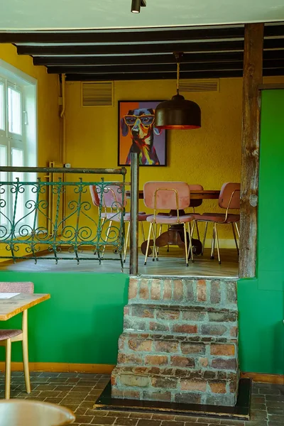 Groene wand met een bakstenen trapje naar het hogere gedeelte van het restaurant