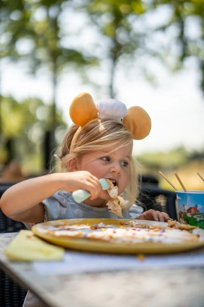 Kind met Pluis-muizenoortjes eet pannenkoek op het terras van Familierestaurant Pluis