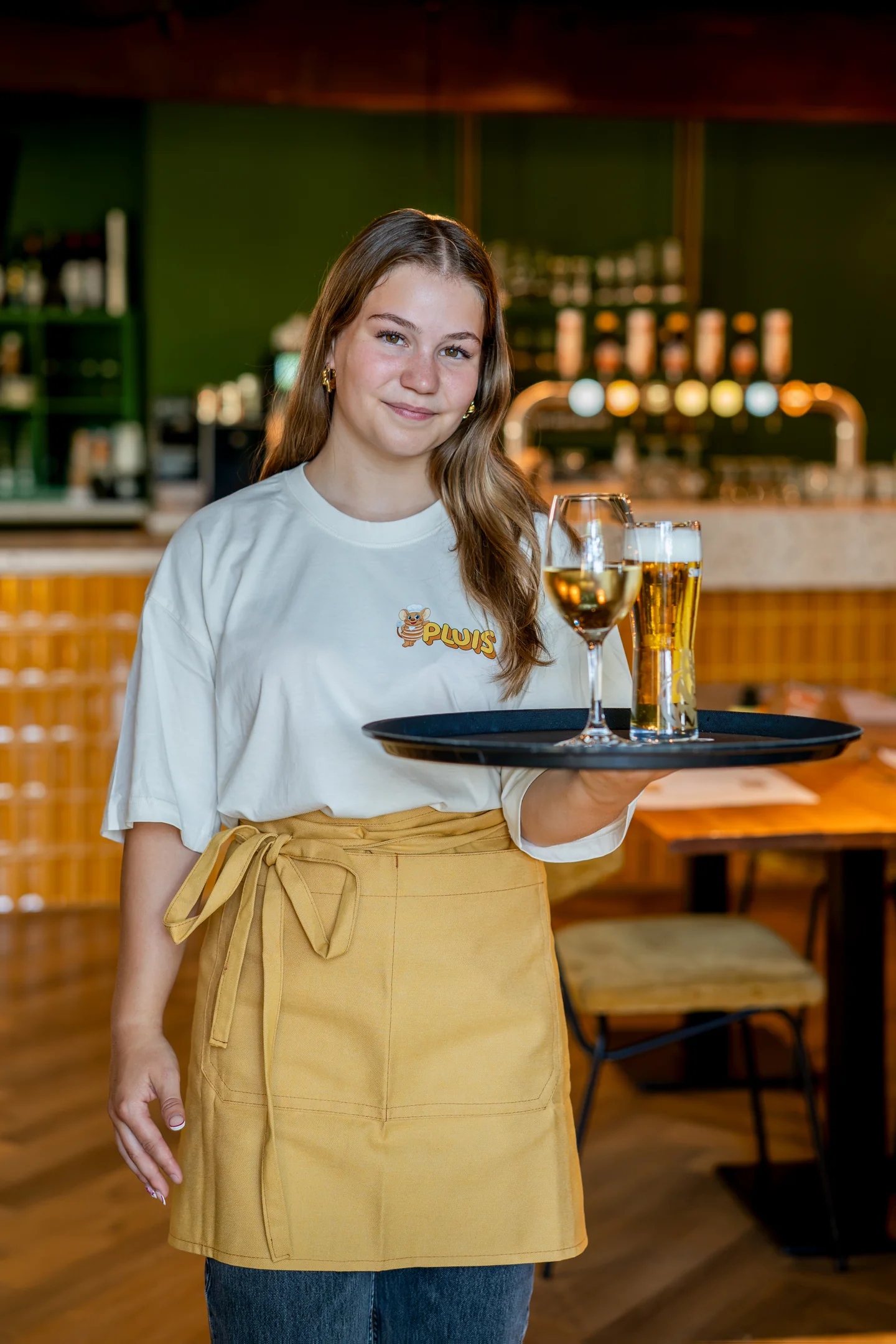 Medewerker van Pluis met dienblad met wijn en bier aan de bar in Aarle-Rixtel