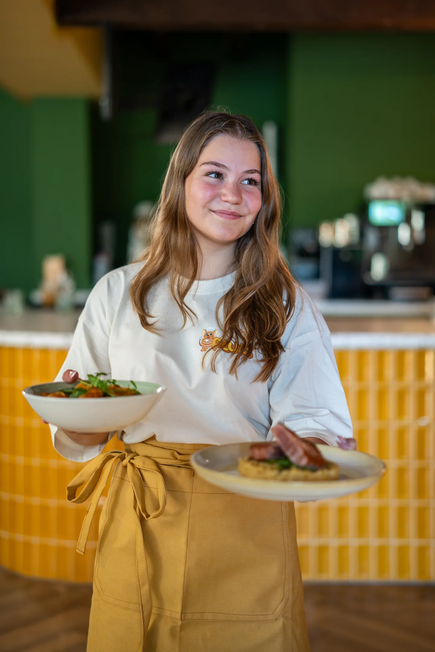 Medewerker van Pluis serveert twee gerechten in het restaurant in Aarle-Rixtel