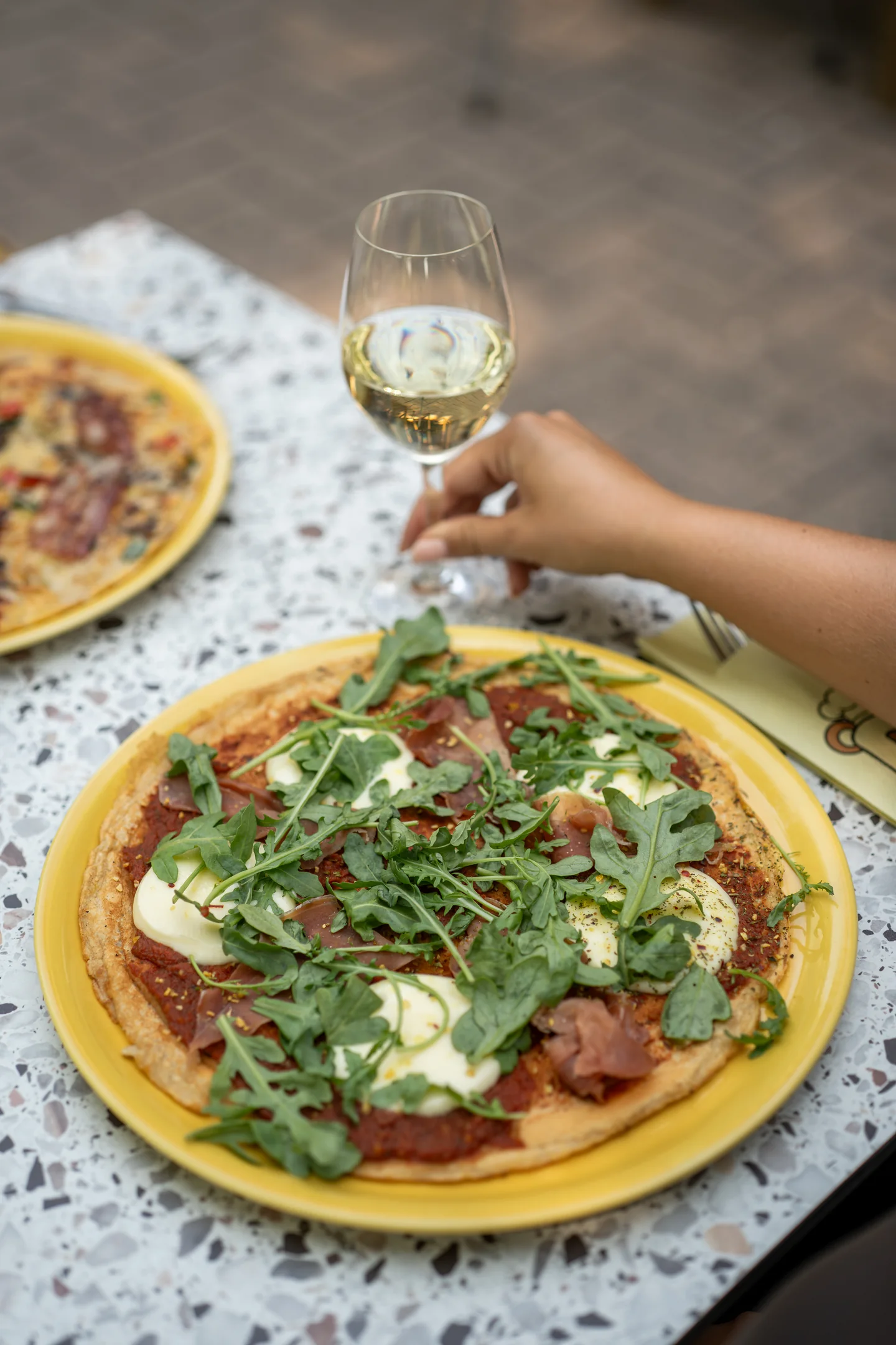 Pannenkoek met ham, mozzarella en rucola op geel bord bij Pluis
